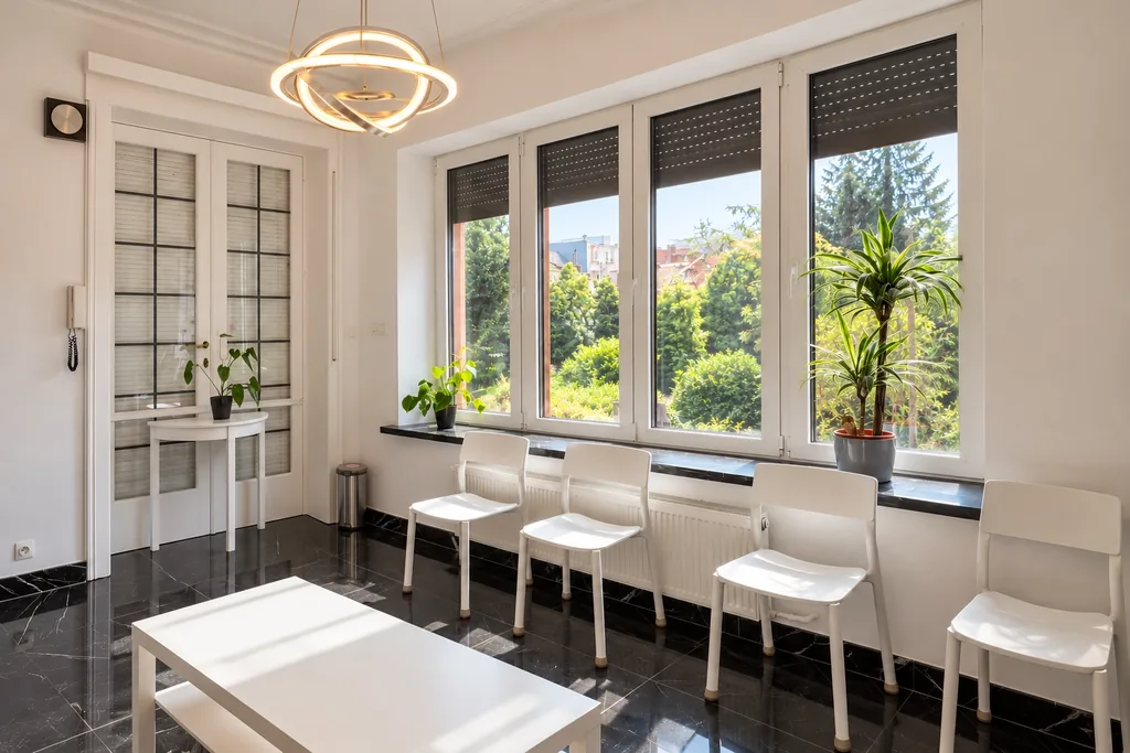 Salle d'attente lumineuse, grandes fenêtres donnant sur le jardin